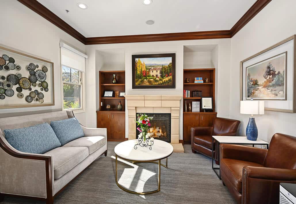 Inviting living room area with a fireplace and seating, adorned with decorative art and a floral centerpiece.