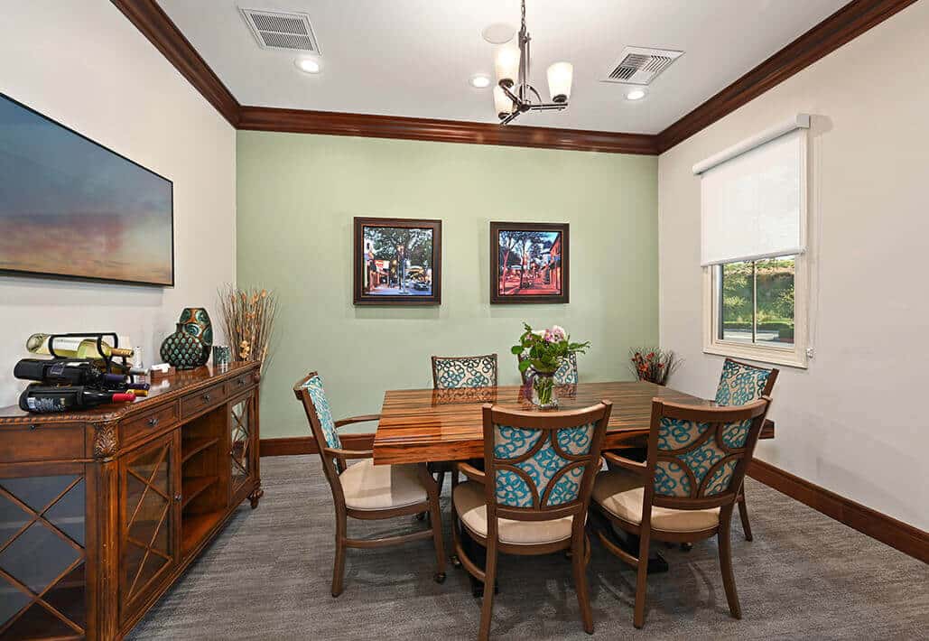 Elegant meeting room with a wooden table, colorful chairs, paintings, and decor items.