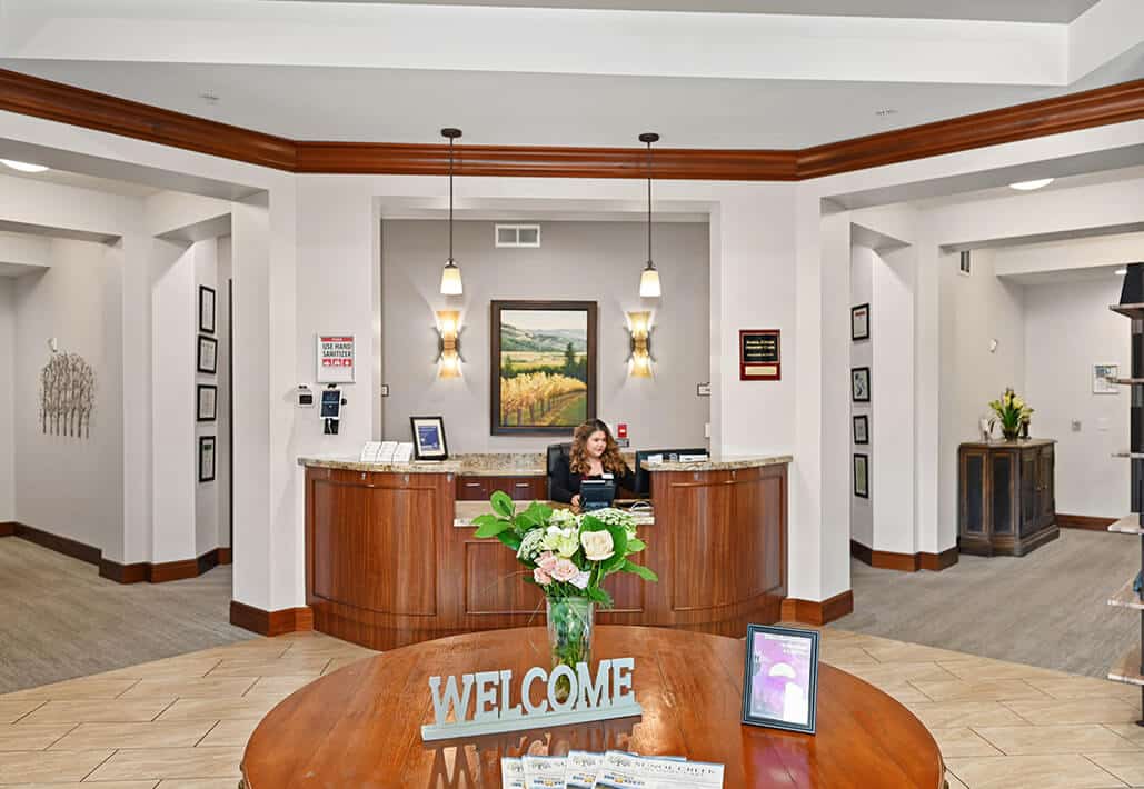 Bright reception area of a senior living community with a welcoming desk and sitting area.