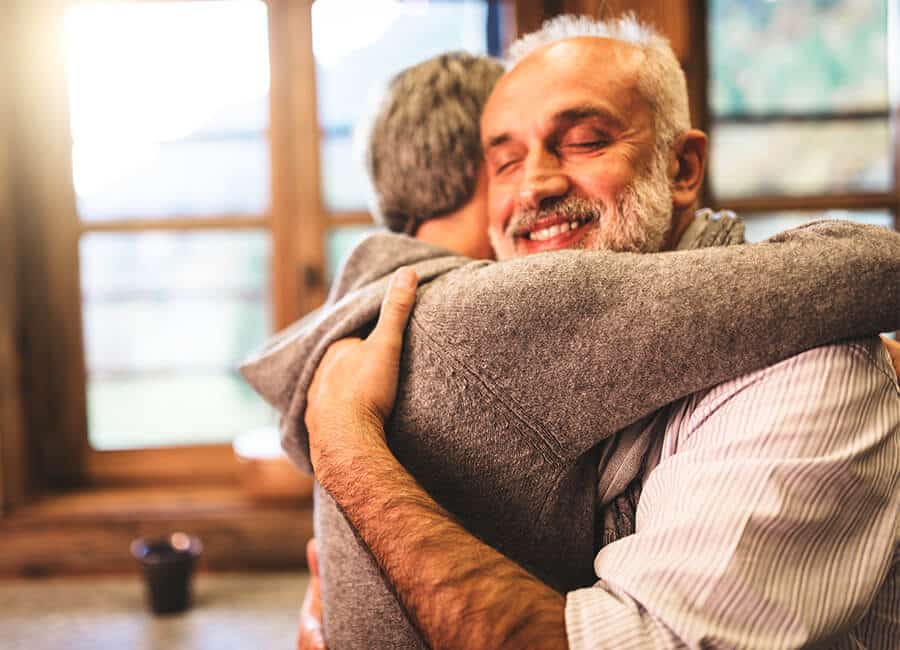 Senior man smiles and hugs a loved one.